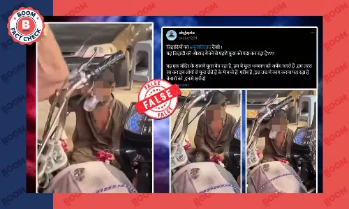 boy spitting water on flowers outside temple in India Pakistan boy spitting water on flowers outside temple in India Pakistan